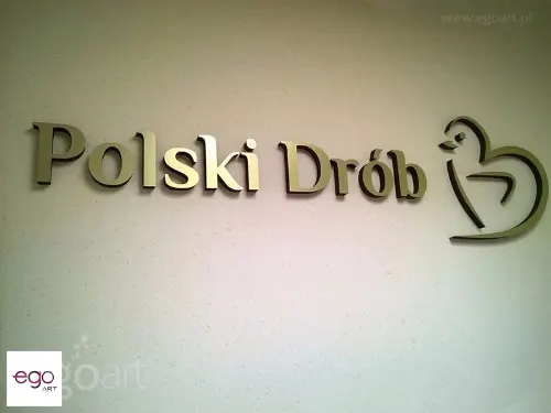 Przestrzenny napis Polski Drób i znak firmowy ze złotym licem na jasnej ścianie.
