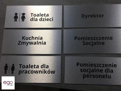 Srebrne tabliczki opisowe z oznaczeniami toalet i zaplecza