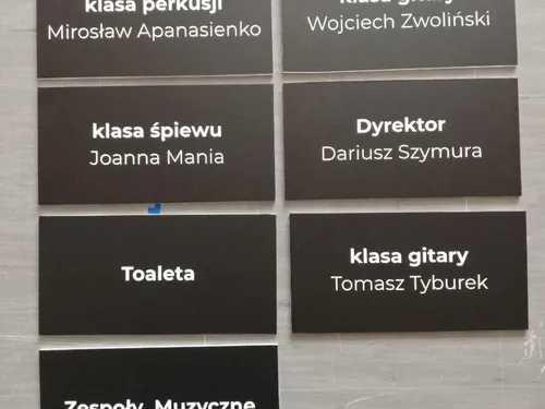 Czarne tabliczki sal i gabinetów szkoły muzycznej