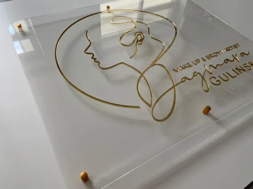 Logo ze złotej plexi lustrzanej na ścianie