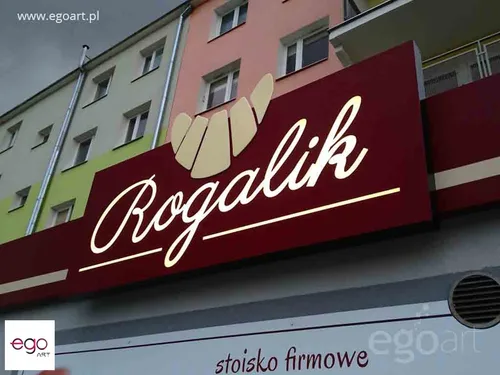 Bordowy kaseton z dibondu z jasnym logo Rogalik nad stoiskiem firmowym.