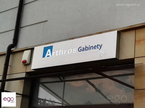 Biały kaseton gabinetów Arthros nad wejściem