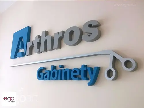 Szaro-niebieskie logo Arthros Gabinety z przestrzennym motywem medycznym na ścianie.
