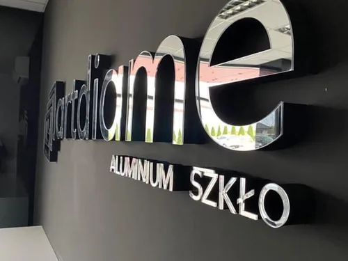 Duży lustrzany napis firmowy z ciemnymi bokami i mniejszym napisem Aluminium Szkło.