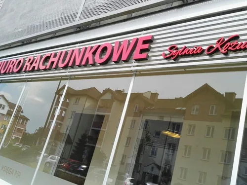 Czerwony przestrzenny napis Biuro rachunkowe zamontowany nad przeszkloną witryną.