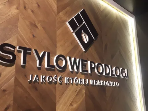 Przestrzenny napis Stylowe Podłogi z czarnym licem i białymi bokami na drewnianym tle.