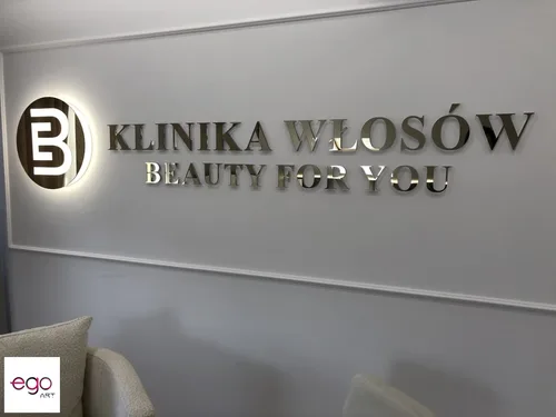 Lustrzane logo Klinika Włosów Beauty For You na jasnej ścianie w salonie.