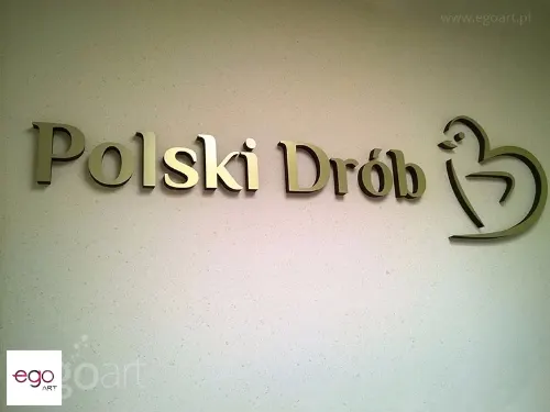 Przestrzenny napis Polski Drób i znak firmowy ze złotym licem na jasnej ścianie.