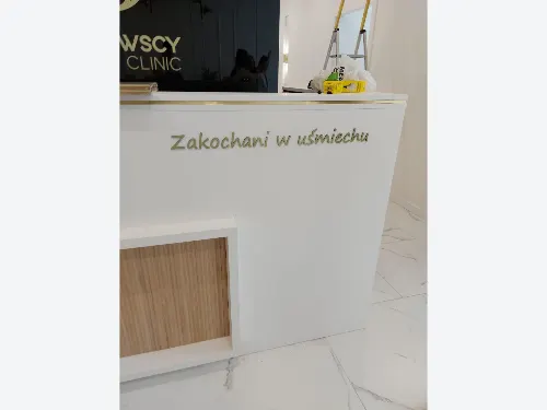 Złoty napis Zakochani w uśmiechu ze szczotkowanego dibondu na froncie białej lady.