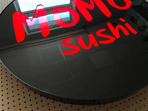 Czerwone podświetlenie liter Momo Sushi na czarnym licu