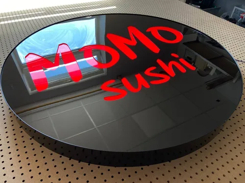 Okrągłe logo Momo Sushi — detal błyszczącej powierzchni