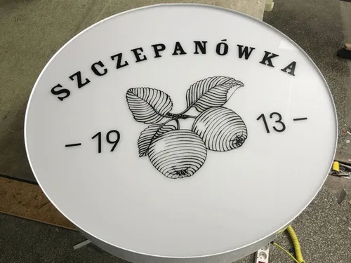 Okrągłe logo z podświetleniem LED z plexi i taśmy alu.