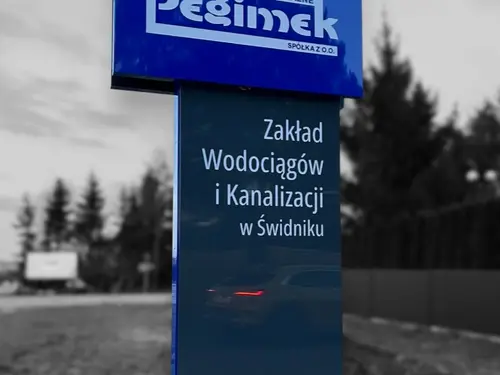Niebiesko-grafitowy pylon z oznaczeniem Zakładu Wodociągów i Kanalizacji w Świdniku.