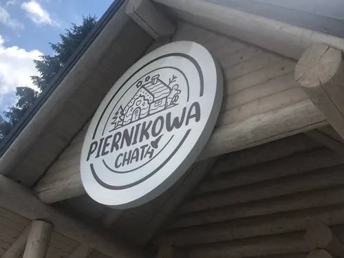 Okrągły kaseton z białymi bokami i licem z plexi z nadrukiem logo Piernikowa Chata.