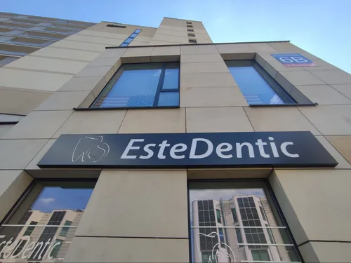 Prostokątny kaseton LED EsteDentic z logo zęba, zamontowany na elewacji gabinetu.