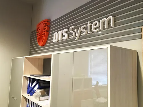 Czerwony znak i białe litery przestrzenne DTS System na ścianie wewnątrz biura.