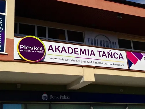 Długa plansza z dibondu z logo Pleskot i napisem Akademia Tańca na elewacji budynku.