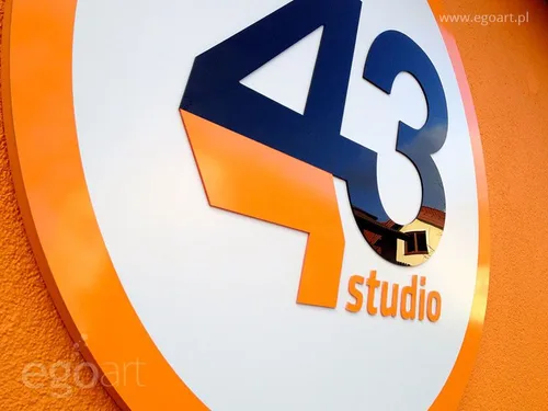 Przestrzenne logo Studio 43 z malowanego styroduru i czarnej plexi na okrągłym tle.