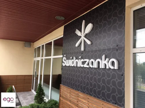 Ciemny szyld z dibondu z białym wypukłym logo i napisem Świdniczanka nad wejściem do lokalu.