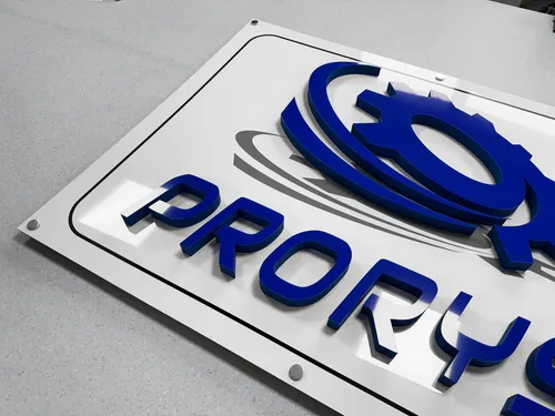 Przezroczysta tablica na dystansach z niebieskim logo i literami przestrzennymi z licem z plexi.