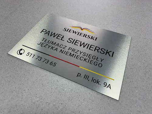 Srebrna tabliczka z nadrukiem UV, logo i napisem tłumacza przysięgłego języka niemieckiego.