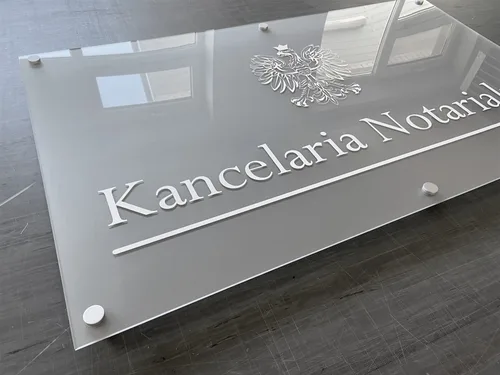 Tablica z mrożonej plexi z białym godłem, napisem Kancelaria Notarialna i srebrnymi dystansami.