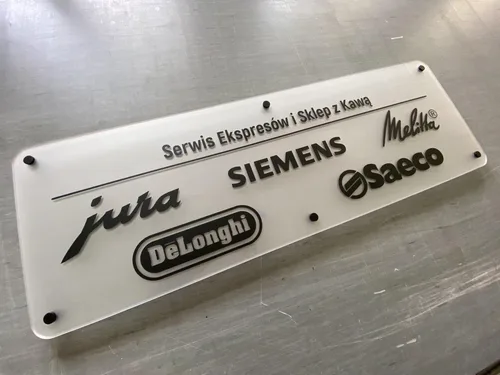 Tablica z mrożonej plexi z czarnymi logotypami marek ekspresów do kawy na czarnych dystansach.