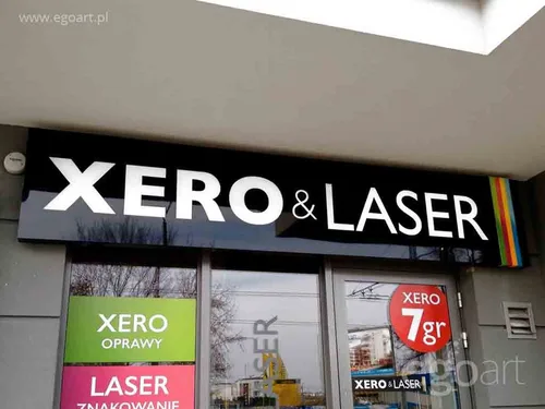 Czarny błyszczący kaseton z dibondu z białym napisem Xero i Laser nad witryną punktu usługowego.