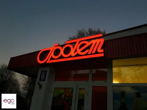 Czerwone logo Społem świecące po zmroku