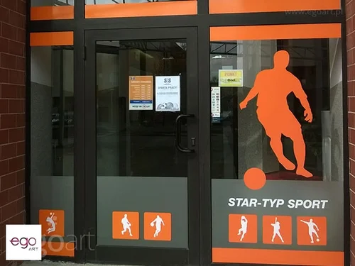 Pomarańczowe sylwetki sportowe na szybach sklepu