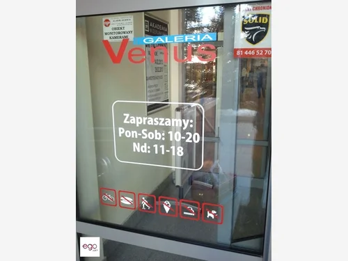 Godziny otwarcia i piktogramy na drzwiach galerii